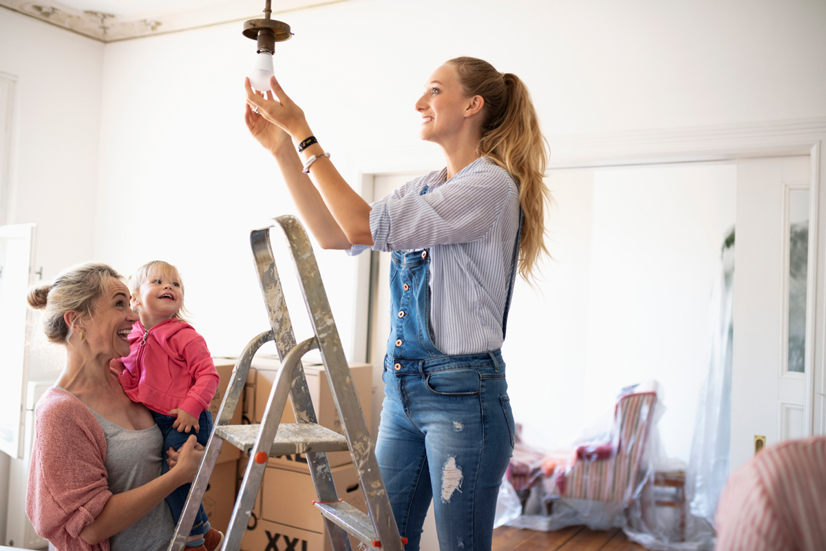 Woman on a chair putting in a light bulb