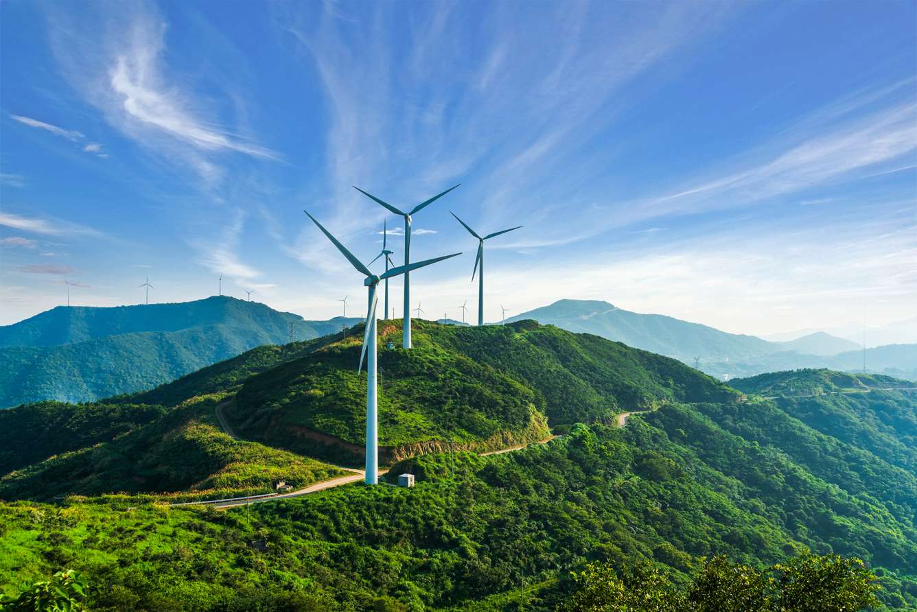 Wind turbines on hill against blue sky