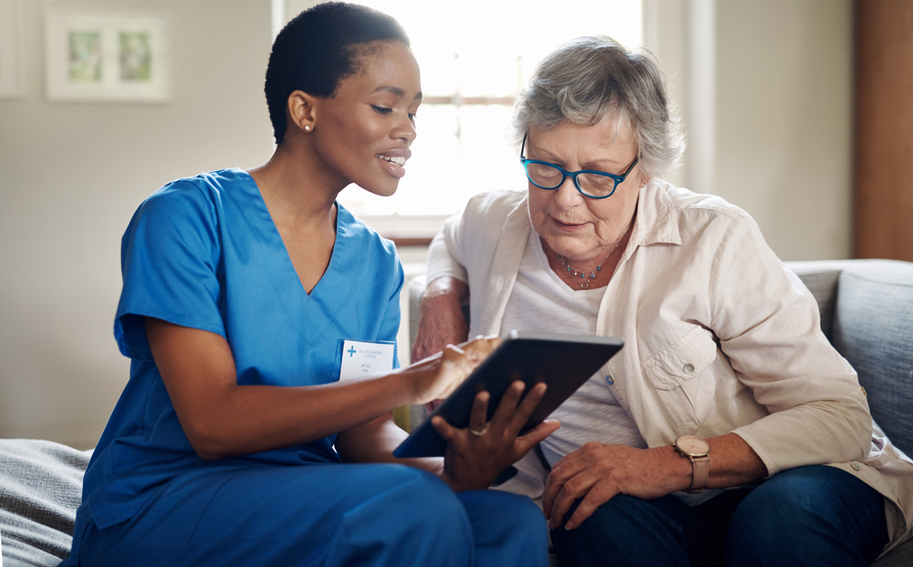 Elderly woman with young nurse using technology