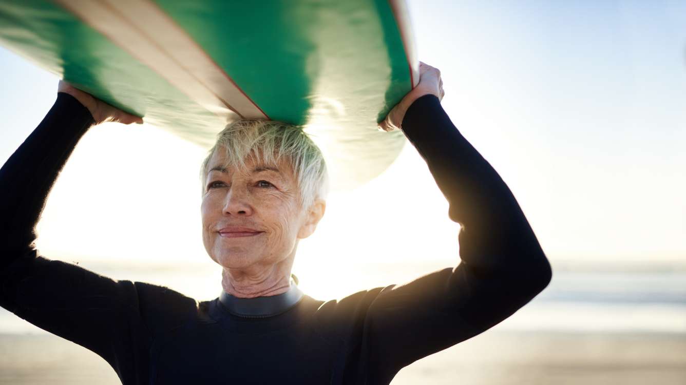 Older woman holding surfboard