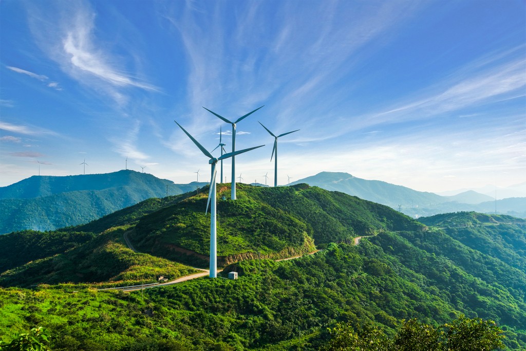 Wind turbines on hill against blue sky