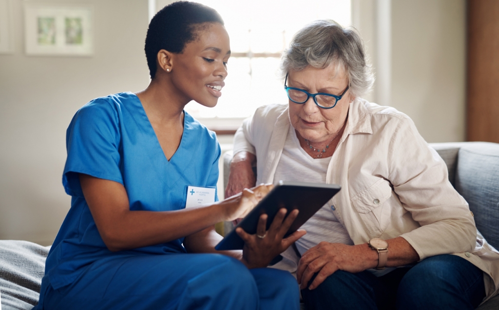 Elderly woman with young nurse using technology