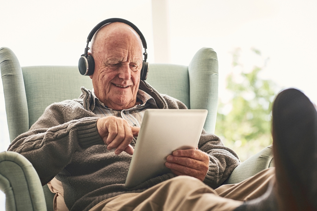 Older man with an iPad and headphones