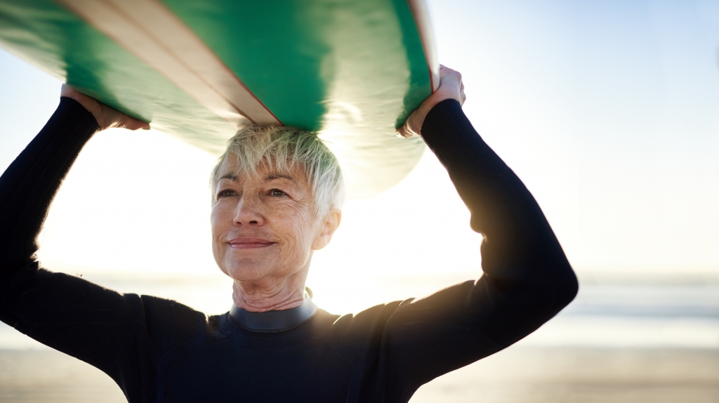 Older woman holding surfboard